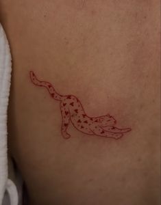 a small tattoo on the back of a woman's stomach that is red and white