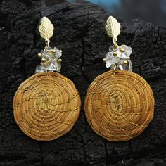 Handcrafted of golden grass these spiral dangle earrings are presented by Brazilian duo Wagner and Cassia. They wrap each earring holding the fibers together with golden threads to hang from 18k gold plated brass hooks with leaf shapes. Quartz bead clusters float at the top of each earring.