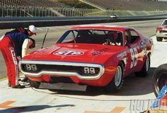 two men working on a red race car