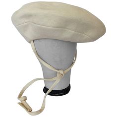 This vintage Yves Saint Laurent cream wool tam style hat, circa late 1960's, is too chic to ignore. This hat features a cream wool exterior along with cream pin stripe top stitch detail, Wide flat top/brim, and Two long wool ties with fringed ends which measure at 21" long. The elastic band at underside ensures a snug fit. Interior is fully lined in grey silk faille. Unmarked Fabric Content: Shell: Wool, Lining: Silk. Measurements: Total Hat Diameter: 13" Elastic Band Diameter (Flat): 7" Fringe Hat, Art Deco Hats, Tam Hat, French Beret Hat, Dior Hat, Beret Style, Saint Laurent Accessories, Vintage Yves Saint Laurent, French Beret