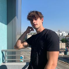 a young man poses for the camera on a balcony