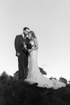 a bride and groom pose for a photo in the tall grass at their wedding day