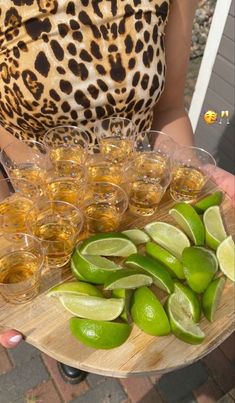 a person holding a tray filled with glasses and limes