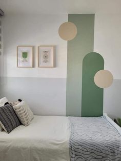 a white bed sitting under two paintings on the wall