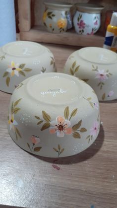 three white dishes sitting on top of a wooden table