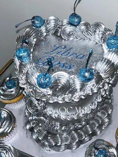 a silver cake with blue frosting and some cupcakes