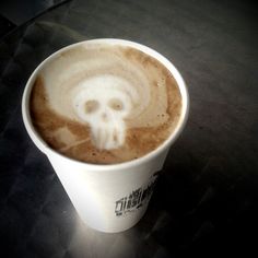 there is a coffee with a skull in the foamy cup on the table top