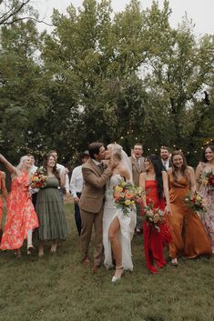 a group of people standing around each other in a field with trees and lights behind them