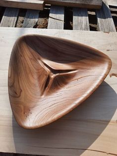 a wooden bowl sitting on top of a piece of wood