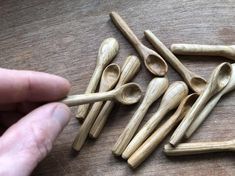 several wooden spoons are arranged on a table with one hand pointing at them and the other