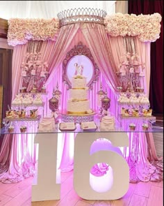 a table topped with a cake covered in frosting and surrounded by pink flowers on top of a wooden floor