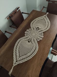 three crocheted doily sitting on top of a wooden table next to chairs