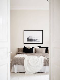 a bed sitting in a bedroom next to a white door with black pillows on top of it