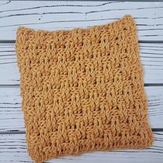 an orange crocheted pillow sitting on top of a wooden floor