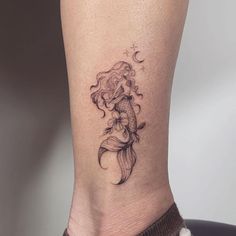 a woman's leg with a tattoo on it that has a mermaid sitting on top of a fish