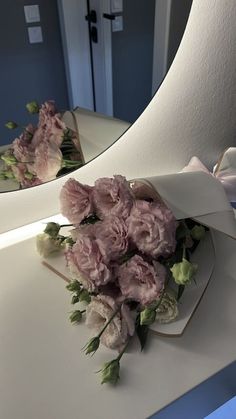 a bouquet of pink flowers sitting on top of a white counter next to a mirror