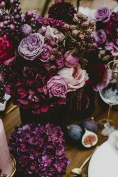 a table topped with lots of purple flowers and candles on top of a wooden table