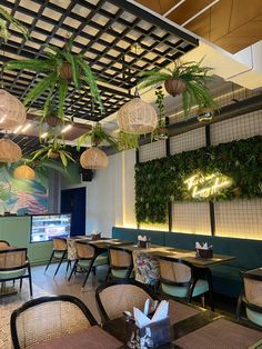 the interior of a restaurant with tables, chairs and plants hanging from the ceiling above them