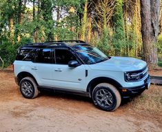 a white suv parked in front of some trees