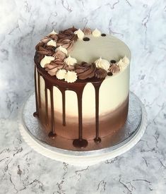 a chocolate cake with white frosting and flowers on top sitting on a marble table