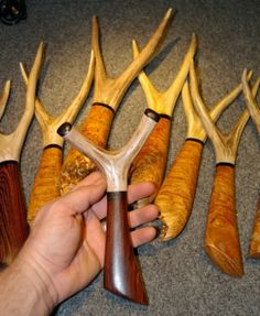 a hand is holding an antler in front of several different sized antlers on the floor