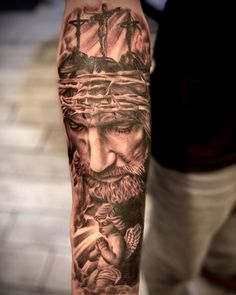 a man with a cross and jesus tattoo on his arm