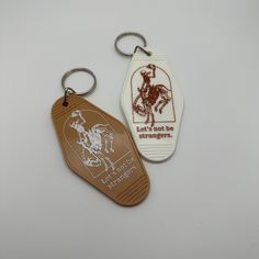 two key chains with the words let's not be strangers written on them, and an image of a cowboy riding a horse