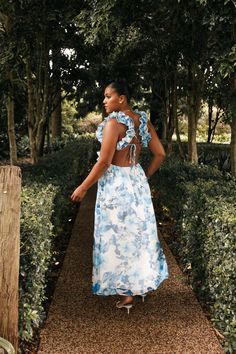 a woman in a blue and white dress standing on a path