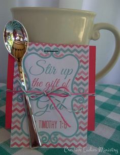 a cup and spoon sitting on top of a table next to a card with the words stir up the gift