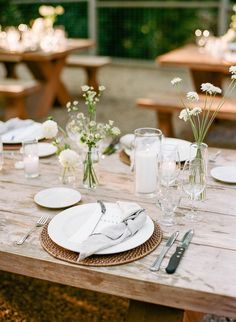 the table is set with plates and silverware, flowers in vases, and candles