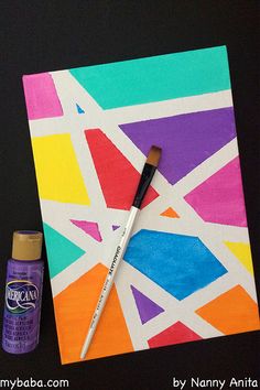 a paintbrush sitting on top of a piece of art paper next to a painting