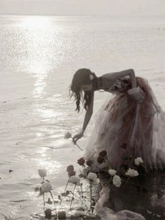 a woman is standing in the water with flowers