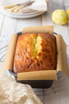 a loaf of pound cake sitting on top of a cooling rack next to some lemons