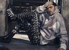 a man sitting on the ground wearing black and white patterned pants with his hands in his hair