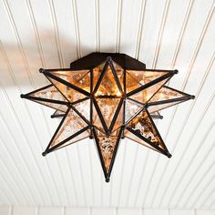 a star light hanging from the ceiling in a room with white painted wood paneling