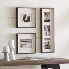 three framed pictures hang on the wall above a table with candles and vases next to it