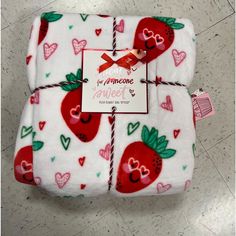 two blankets with hearts and strawberries on them, one has a tag attached to it