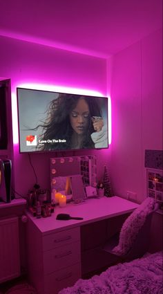 a bedroom with purple lighting and a flat screen tv mounted on the wall above a desk