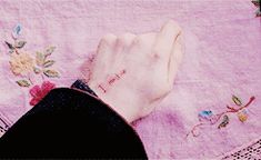 a person's hand on top of a pink table cloth