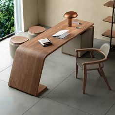 a wooden desk sitting in front of a window next to a chair and bookshelf