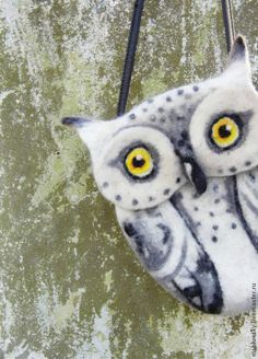 an owl purse with yellow eyes hanging from a hook on a concrete wall, close up