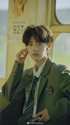 a young man in a green suit listening to headphones while sitting on a bus