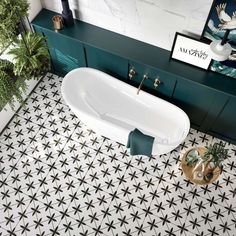 a bath tub sitting on top of a bathroom floor next to a green cabinet and potted plant