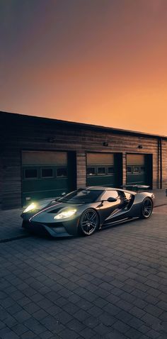 a black sports car parked in front of two garages at night with the sun setting