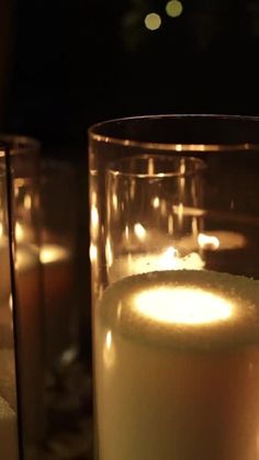 lit candles are in glass cups on a table