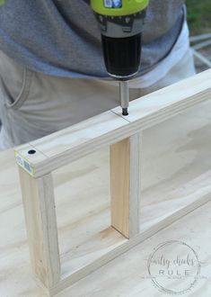 a man using a drill to attach the top of a piece of wood on a table