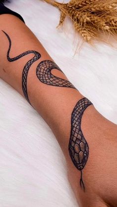 a woman's arm with a snake tattoo on it