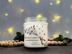 a glass jar filled with white candles sitting on top of a table next to wooden beads