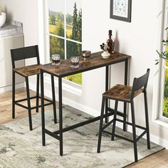 a table with two stools in front of a window and a rug on the floor