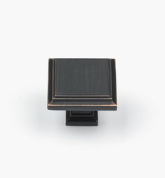 a black square knob with gold trim on an isolated white background for use in cabinet doors or drawer pulls